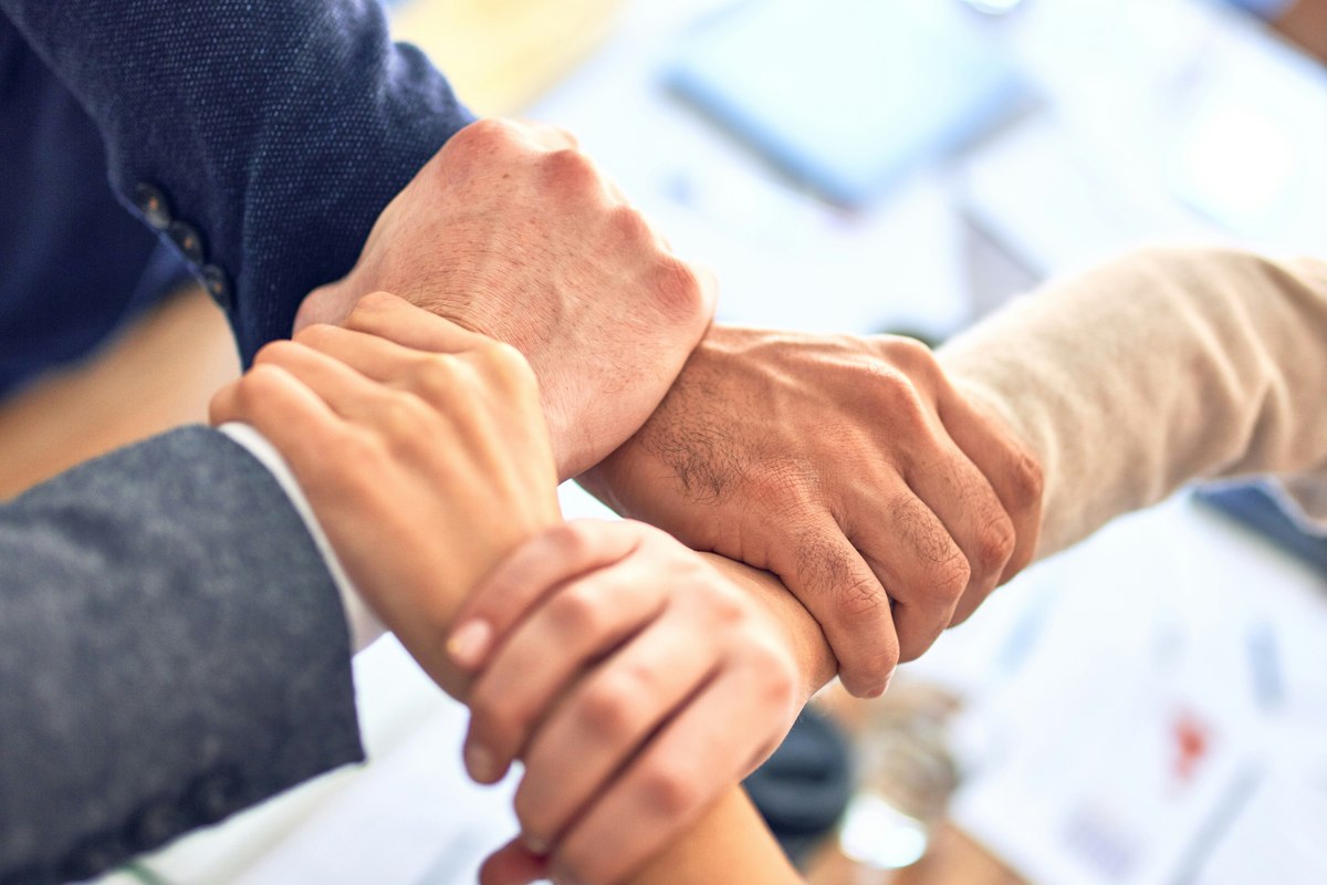 Four business partners clasping wrists together in a gesture of unity